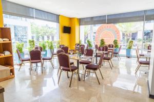 a dining room with tables and chairs and windows at GHL Style Barrancabermeja in Barrancabermeja