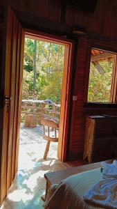 een slaapkamer met een deur die uitkomt op een veranda met een terras bij Pousada Toque de Minas in Visconde De Maua