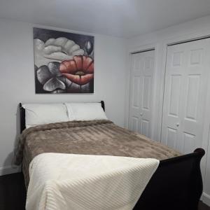 een slaapkamer met een bed met een schilderij aan de muur bij Ici Chez Vous in Trois-Rivières