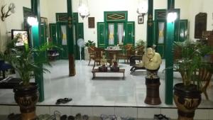 a room with green doors and a room with a statue at Pendopo Andari Homestay in Yogyakarta