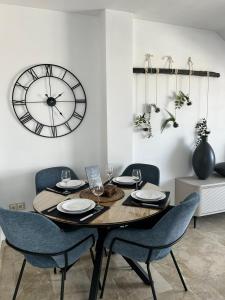 een eettafel met stoelen en een klok aan de muur bij Luz del Sur in Antequera