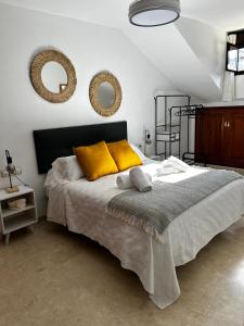 een slaapkamer met een bed met gele kussens en spiegels bij Luz del Sur in Antequera