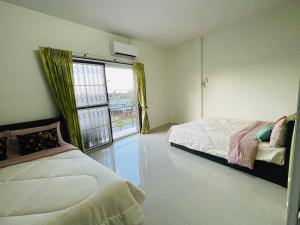 ein Schlafzimmer mit zwei Betten und einem großen Fenster in der Unterkunft ท่าบูรพาวิลล่า ที่พักพร้อมสระน้ำ ทั้งหลัง in Ban Hua Khao Sammuk