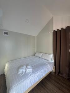 een wit bed met twee witte handdoeken erop bij JAYLA Resort in Sattahip