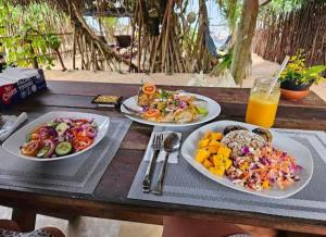 three plates of food on a wooden table with orange juice at Waves ranna cabana and seafood in Ranna
