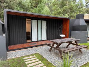 a small cabin with a picnic table and a chair at La Posada Bungalows in Necochea