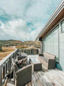 a balcony with chairs and a coffee table on a building at Charming Cabin Overlooking Vegglifjell in Kravikfjord