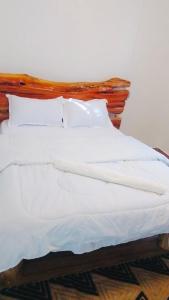 een bed met witte lakens en kussens erop bij Terus studio in Nanyuki