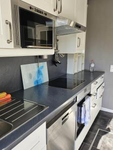 a kitchen with white cabinets and a black counter top at Zum Leuchtturm in Heiligenhafen