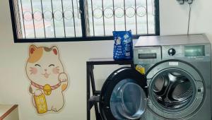 une machine à laver avec un chat peint sur le mur dans l'établissement ท่าบูรพาวิลล่า ที่พักพร้อมสระน้ำ ทั้งหลัง, à Ban Hua Khao Sammuk