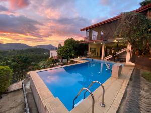 a swimming pool in front of a house with a sunset at Hotel H2O in Gampola