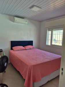 a bedroom with a bed with pink sheets and a window at Casa completa Centro de Xangri-lá, perto do mar in Xangri-lá