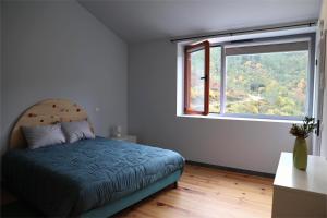 een slaapkamer met een bed en een groot raam bij MedronHouse - Casa de Campo in Vasco Esteves de Baixo
