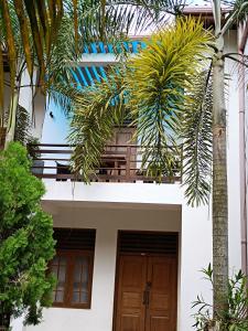 een wit huis met palmbomen ervoor bij Villa Four Seasons in Mirissa