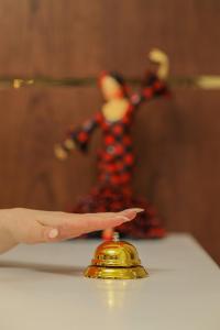 Een hand wijst naar een gouden bel op een tafel. bij Barca Hotel in Jerevan