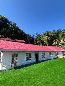 ein Gebäude mit rotem Dach und grünem Rasen in der Unterkunft Baas Basai in Kalimpong