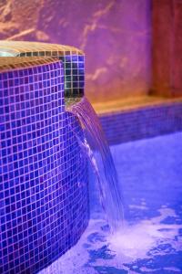 une fontaine dans une piscine aux carreaux violets dans l'établissement Barca Hotel, à Erevan