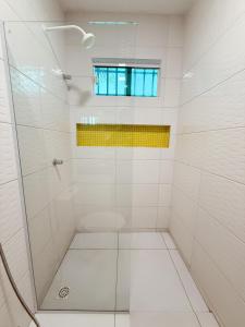 a white bathroom with a shower with a window at Pousada Cidade Nova in Campo Maior