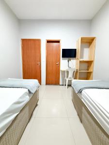 a hotel room with two beds and a tv at Pousada Cidade Nova in Campo Maior