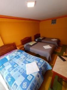 een kamer met drie bedden en een tafel erin bij WILLKA Hostel in Copacabana
