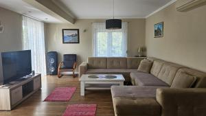 een woonkamer met een bank en een flatscreen-tv bij Villa Longina in Ljubuški