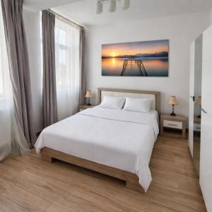 a white bedroom with a large bed and a window at Apartamente Livada in Râmnicu Vâlcea