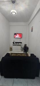a bedroom with a bed and a tv on a wall at Flat Saigon Barra de Maricá Pé na Areia Wi-Fi in Maricá