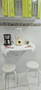 a table with two chairs and a blender on a counter at Flat Saigon Barra de Maricá Pé na Areia Wi-Fi in Maricá +22 photos