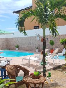 een patio met stoelen en een palmboom naast een zwembad bij Torre do Sol in Praia do Frances