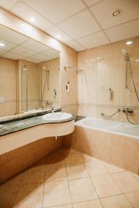 een badkamer met een wastafel, een bad en een spiegel bij Hotel Karpos in Skopje