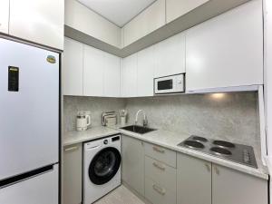 eine Küche mit weißen Schränken und einer Waschmaschine in der Unterkunft Karakol 'Ethno' Apartment in Karakol