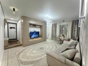 ein Wohnzimmer mit Sofa und Fernseher in der Unterkunft Karakol 'Ethno' Apartment in Karakol