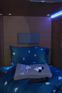 een bed met een blauw bed en een afstandsbediening bij The GreenHouse Capsules in Londen