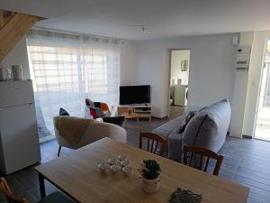een woonkamer met een bank en een tafel bij Maison Les Escardines in Oye-Plage