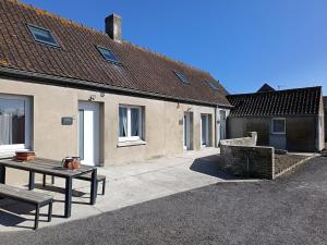 een patio van een huis met een tafel en een bank bij Maison Les Escardines in Oye-Plage