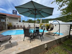 a table and chairs with an umbrella next to a pool at Minha Casa Palmas 2 in Governador Celso Ramos