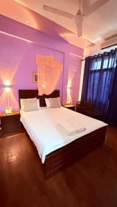een slaapkamer met een groot wit bed met paarse muren bij Subhas Tourist Hotel in Jaffna +75 foto's