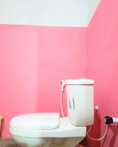 a bathroom with a pink wall and a toilet at Fr Resort in Arugam Bay