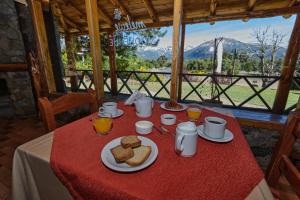 een tafel met een rode tafeldoek met brood erop bij Melewe Moquehue in Moquehue