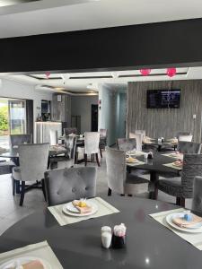 une salle à manger avec des tables, des chaises et une télévision dans l'établissement Pula Nala Lodge Bed & Breakfast, à Rustenburg