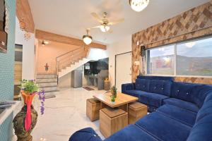 ein Wohnzimmer mit einem blauen Sofa und einem Tisch in der Unterkunft EMPYREAN STAY II LEONCINO VILLA II 4BHK II AC II LARGE POOL lI WIFI II BBQ in Lonavla + 35 Fotos