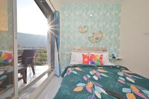 ein Schlafzimmer mit einem Bett mit geblümter Tagesdecke und einem Balkon in der Unterkunft EMPYREAN STAY II LEONCINO VILLA II 4BHK II AC II LARGE POOL lI WIFI II BBQ in Lonavla