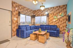 ein Wohnzimmer mit einem blauen Sofa und einem Tisch in der Unterkunft EMPYREAN STAY II LEONCINO VILLA II 4BHK II AC II LARGE POOL lI WIFI II BBQ in Lonavla