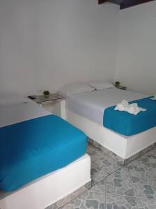a bedroom with a white bed with blue sheets at Posada Doña Carmen in El Roque