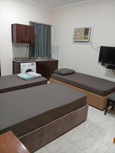 een kleine kamer met 2 bedden en een televisie bij KhavaQatar Hostel 2 بيت مشترك in Doha