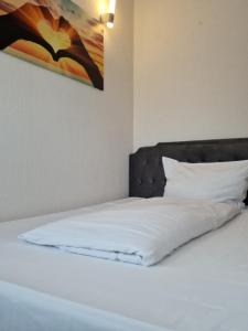 een bed met witte lakens en een schilderij aan de muur bij Pension Pale' Bach in Bad Hersfeld