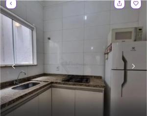 a white kitchen with a sink and a refrigerator at Kit Net Cidade Universitária in Limeira