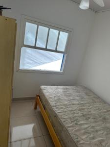een slaapkamer met een bed en een raam bij Conforto a 100 m do mar in Tramandaí