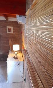 a blind on a wall with a lamp on a table at Cabaña Balcón Serrano in Cortaderas