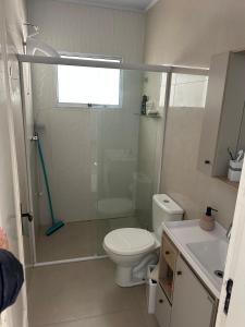een badkamer met een douche, een toilet en een wastafel bij Conforto a 100 m do mar in Tramandaí